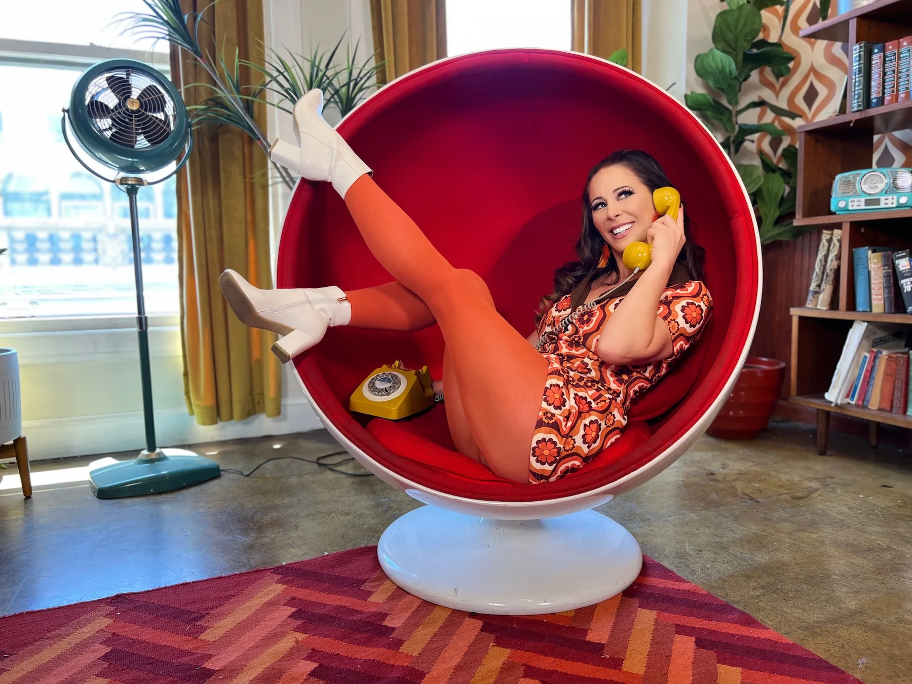 Cherie DeVille relaxes in a retro lounge chair while talking on a vintage telephone, featured in an article about misconceptions about adult work and the realities behind the industry.